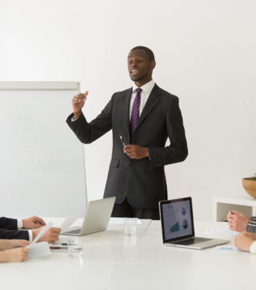 Confident african speaker or business coach giving presentation How to Lead Remote Teams Effectively in a Hybrid Work World